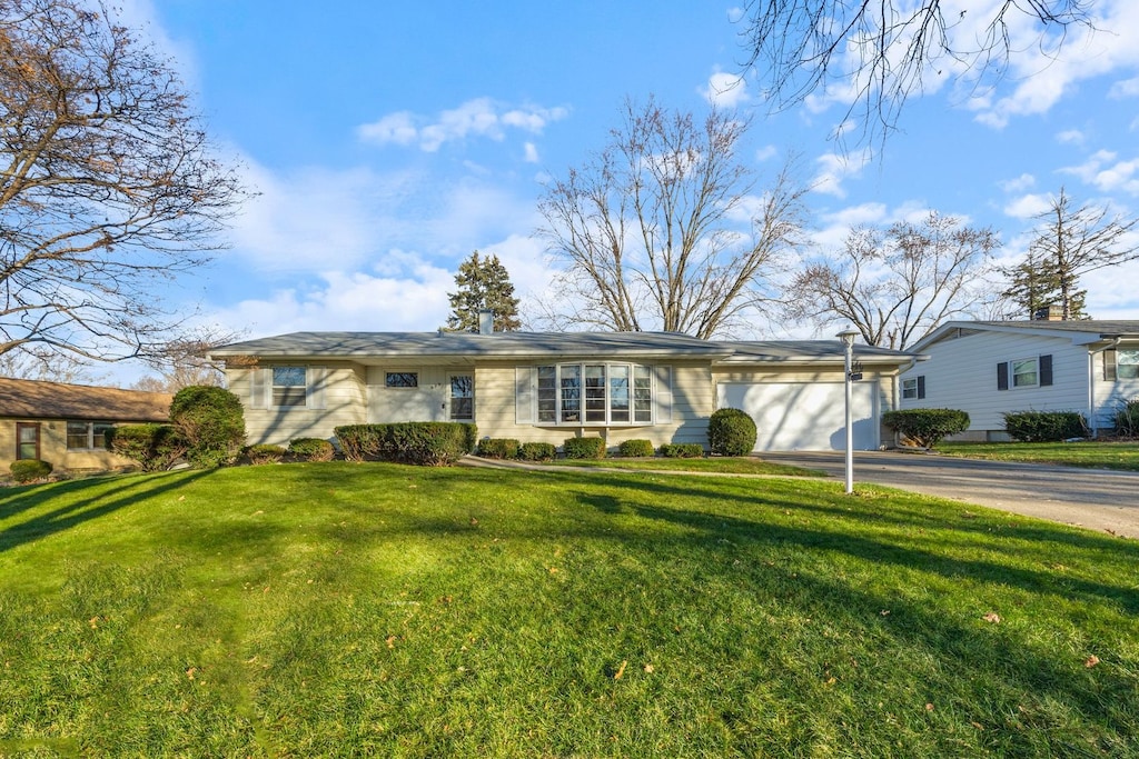 ranch-style house featuring a garage and a front lawn