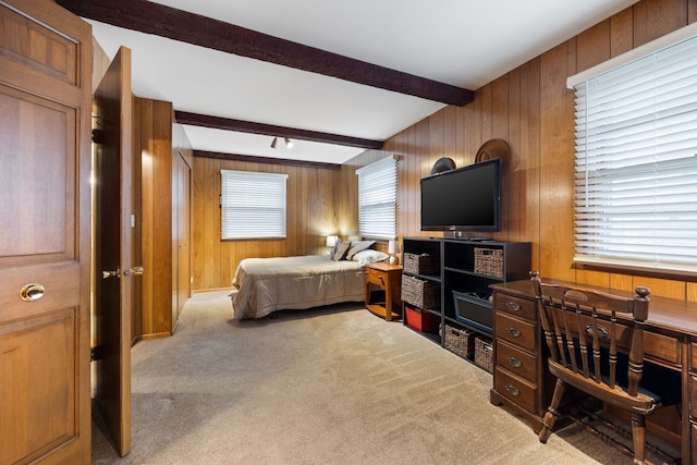 carpeted bedroom with beamed ceiling and wood walls