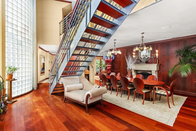 dining space featuring hardwood / wood-style flooring, wooden walls, an inviting chandelier, and ornamental molding