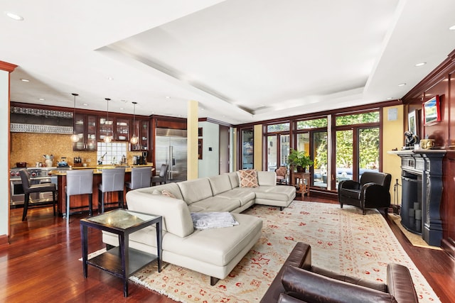 living room with dark hardwood / wood-style flooring and a tray ceiling