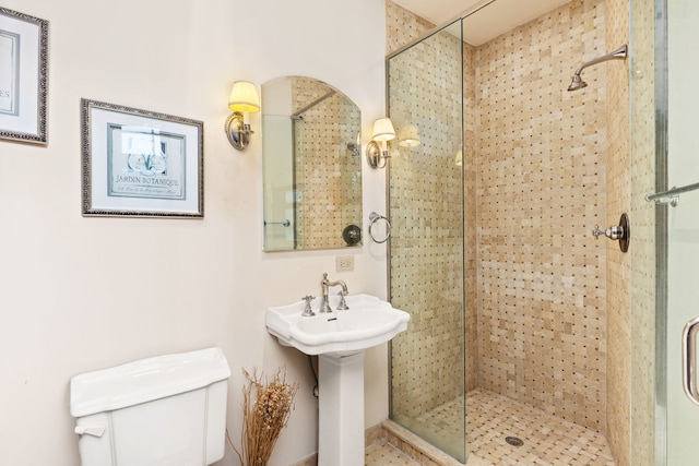 bathroom featuring a shower with shower door and toilet