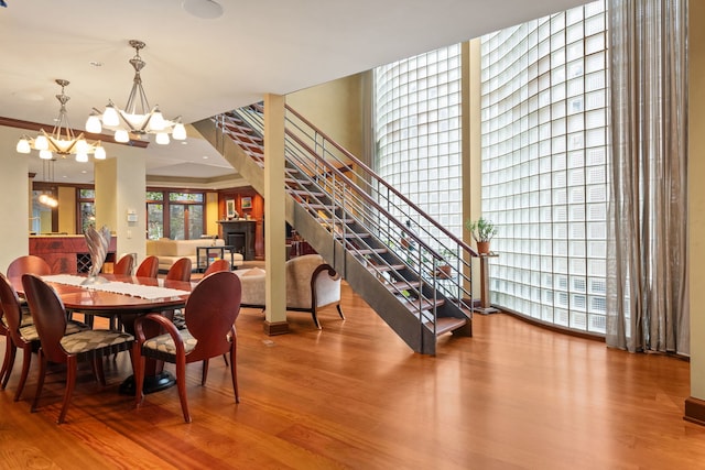 dining area with wood-type flooring, crown molding, and an inviting chandelier