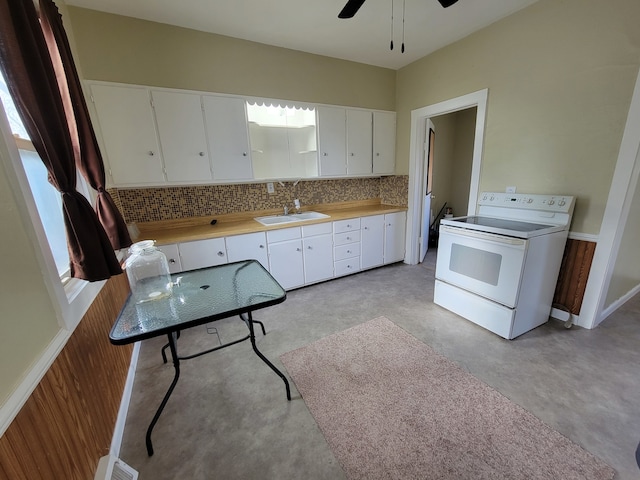 kitchen featuring white range with electric cooktop, backsplash, sink, white cabinets, and ceiling fan