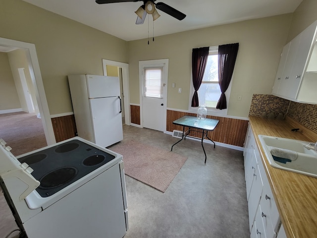 kitchen featuring white cabinets, white appliances, wood walls, and sink