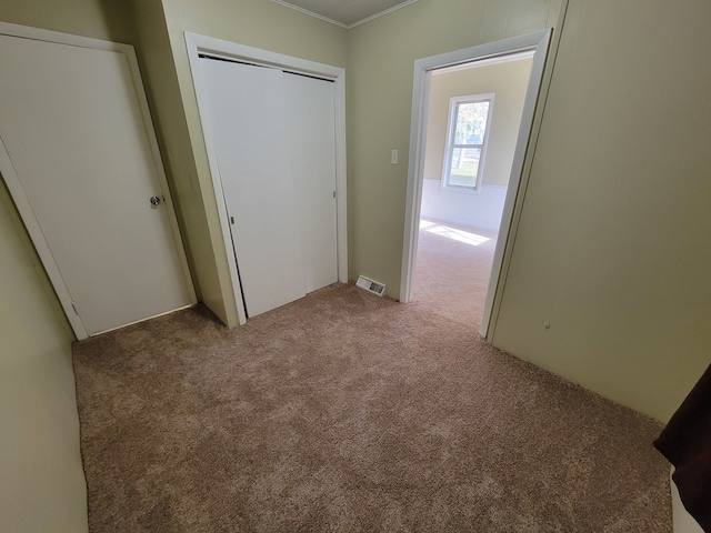 unfurnished bedroom featuring a closet, carpet floors, and ornamental molding