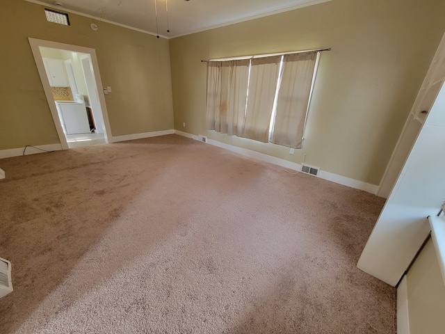 carpeted spare room featuring ornamental molding and washer / dryer