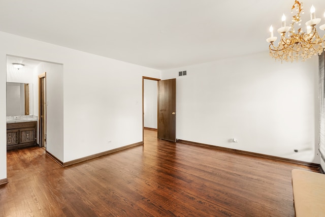 empty room featuring dark hardwood / wood-style flooring and a notable chandelier