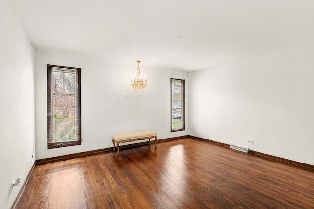 spare room featuring dark hardwood / wood-style flooring and an inviting chandelier