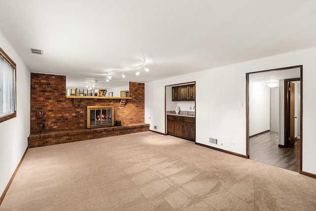 unfurnished living room featuring carpet, indoor bar, and a brick fireplace