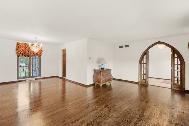 empty room featuring dark hardwood / wood-style floors and an inviting chandelier