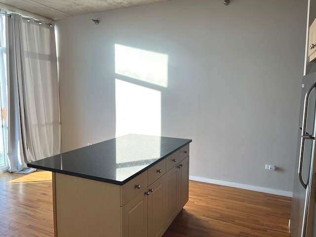 kitchen with stainless steel fridge, white cabinetry, light hardwood / wood-style flooring, and a kitchen island