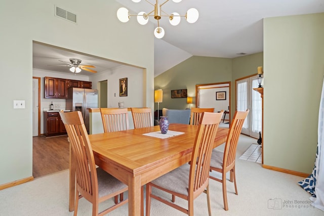 dining space with light carpet, an inviting chandelier, visible vents, and vaulted ceiling