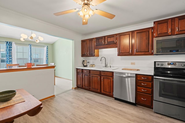 kitchen with light wood finished floors, appliances with stainless steel finishes, decorative light fixtures, light countertops, and a sink