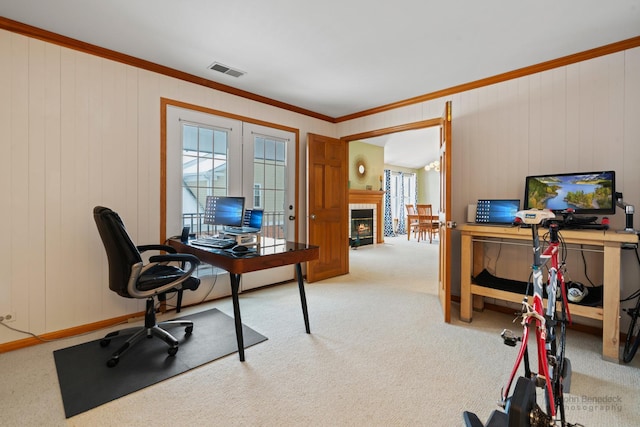 home office with a tile fireplace, light carpet, visible vents, french doors, and crown molding