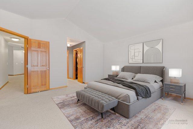 bedroom featuring lofted ceiling, baseboards, and light colored carpet