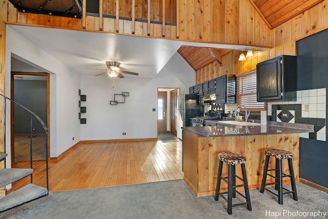 kitchen with wooden ceiling, kitchen peninsula, a kitchen bar, sink, and lofted ceiling