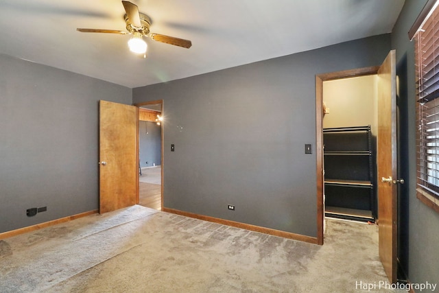 unfurnished bedroom featuring ceiling fan, a spacious closet, a closet, and light carpet