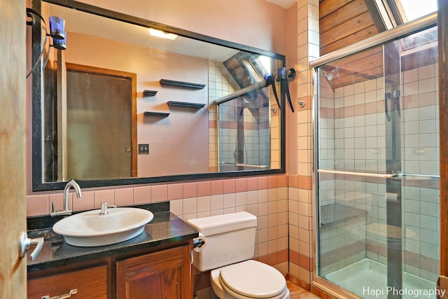 bathroom with toilet, decorative backsplash, tile walls, a shower with shower door, and vanity