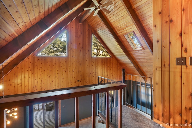 corridor featuring wooden ceiling, wood walls, lofted ceiling with skylight, and carpet