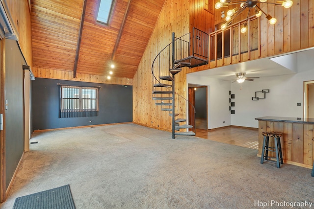 unfurnished living room with wood ceiling, high vaulted ceiling, carpet floors, a skylight, and ceiling fan with notable chandelier