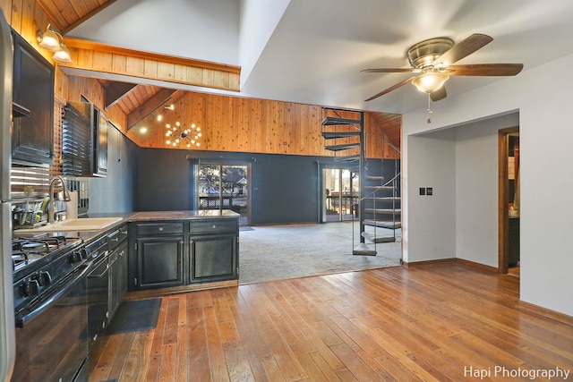 kitchen featuring vaulted ceiling, wood-type flooring, black appliances, ceiling fan, and sink