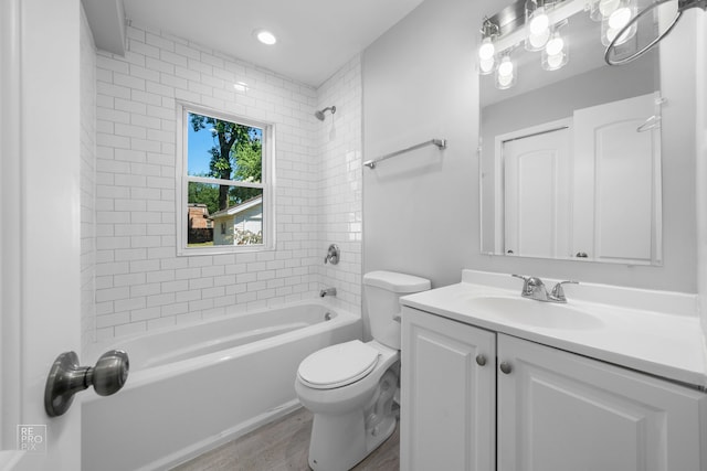 full bathroom featuring hardwood / wood-style floors, vanity, tiled shower / bath combo, and toilet