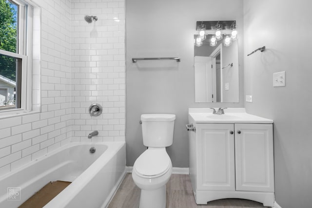 full bathroom with a wealth of natural light, vanity, tiled shower / bath combo, and toilet