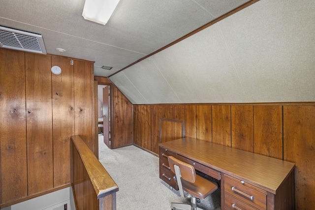 home office featuring lofted ceiling, wood walls, a textured ceiling, light carpet, and built in desk