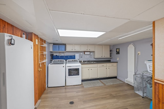 kitchen featuring light hardwood / wood-style floors, white refrigerator, sink, backsplash, and washer and dryer