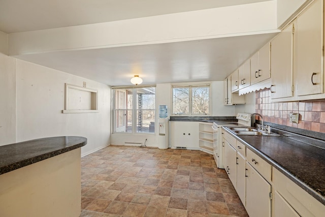 kitchen with electric stove, sink, and dark stone counters