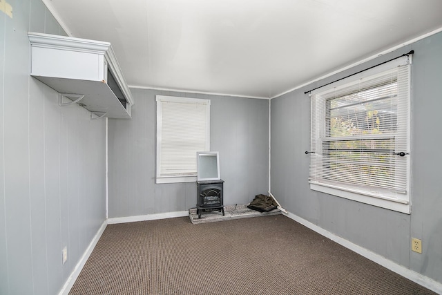 interior space featuring a wood stove, crown molding, and carpet floors