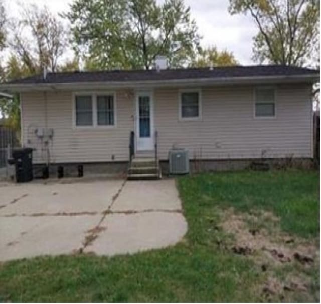 back of house with central air condition unit and a lawn