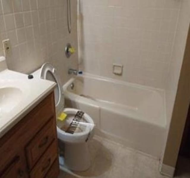 full bathroom featuring toilet, vanity, tiled shower / bath, and tile patterned floors