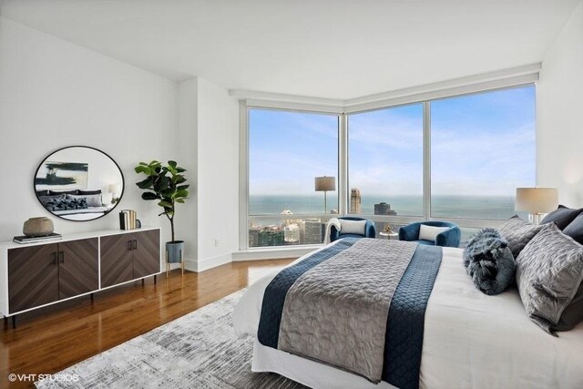 bedroom with hardwood / wood-style floors and a water view