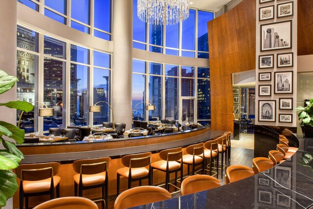 bar featuring a high ceiling, hardwood / wood-style flooring, and a notable chandelier