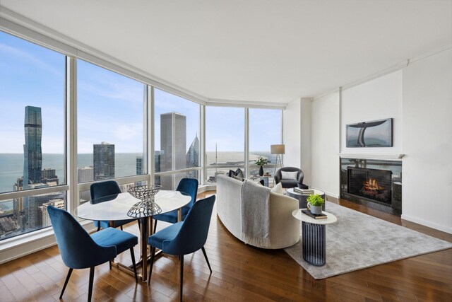 dining space with plenty of natural light, a water view, wood-type flooring, and a wall of windows