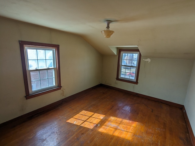 additional living space with lofted ceiling, a healthy amount of sunlight, and dark hardwood / wood-style floors