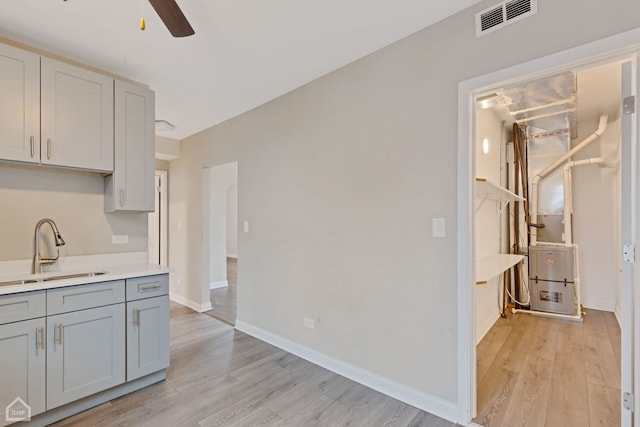 kitchen featuring gray cabinets, ceiling fan, sink, and light hardwood / wood-style flooring