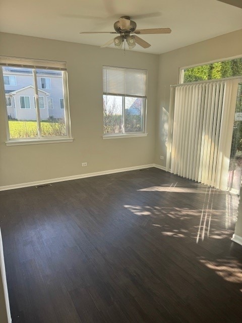 unfurnished room featuring ceiling fan, a healthy amount of sunlight, and dark hardwood / wood-style flooring