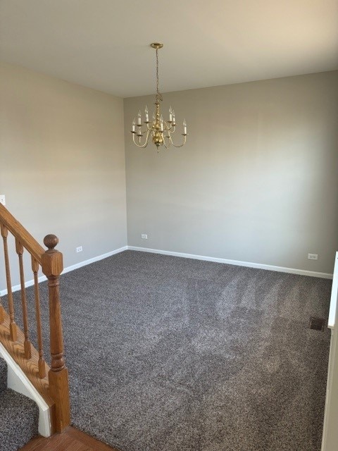 empty room featuring a chandelier and dark colored carpet