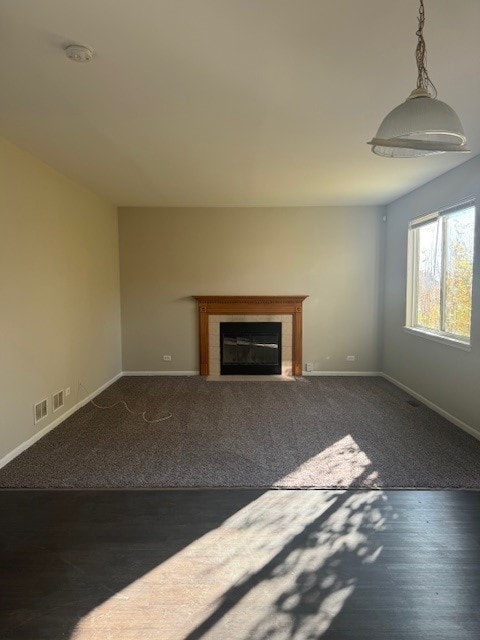 unfurnished living room featuring dark wood-type flooring and a tile fireplace