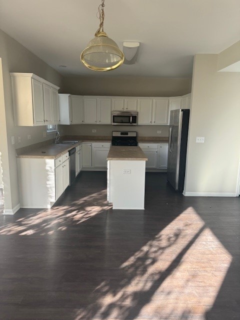 kitchen featuring stainless steel appliances, dark hardwood / wood-style floors, white cabinetry, and a center island