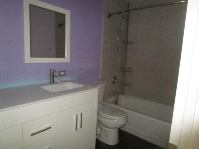 full bathroom featuring vanity, tiled shower / bath combo, and toilet