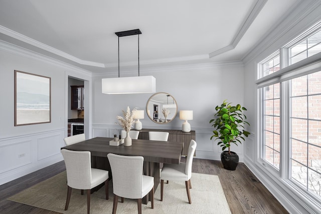 dining space with dark wood finished floors, crown molding, a decorative wall, and wainscoting