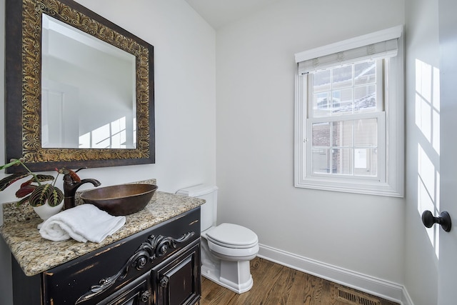 bathroom with vanity, wood finished floors, visible vents, baseboards, and toilet