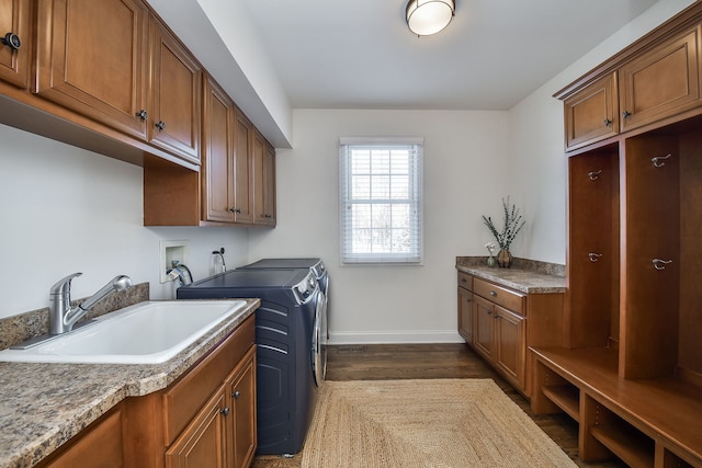 laundry area featuring dark wood-style floors, baseboards, cabinet space, separate washer and dryer, and a sink