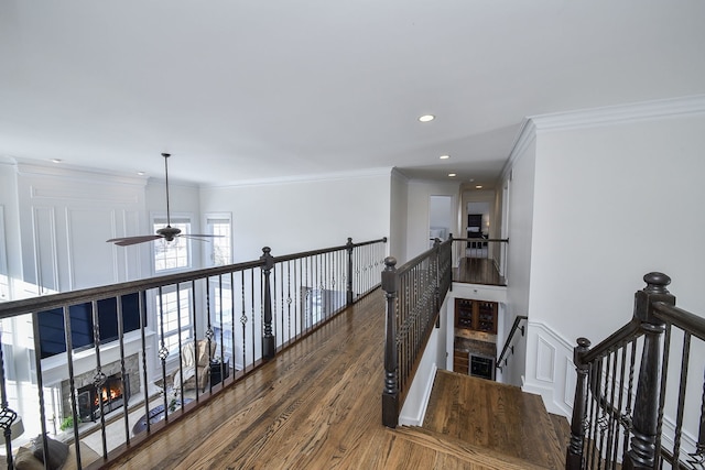 corridor with an upstairs landing, recessed lighting, ornamental molding, and wood finished floors