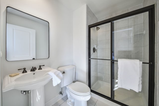 bathroom featuring tile patterned floors, toilet, and a shower stall