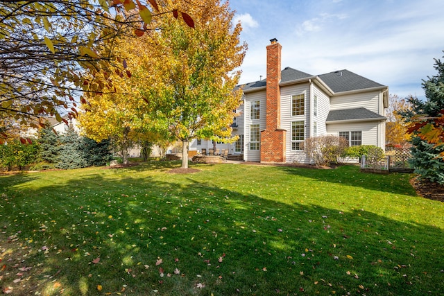 back of house featuring a lawn, fence, and a chimney