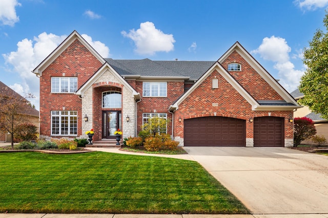 traditional-style house with a shingled roof, a front lawn, concrete driveway, stone siding, and brick siding